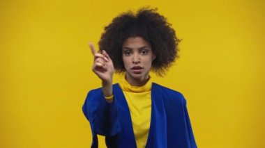 Afro-Amerikalı kadın sarıya izole edilmiş baş parmağını gösteriyor.