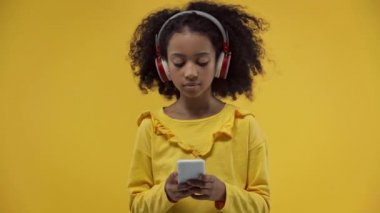 african american kid listening music isolated on yellow 