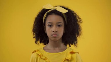 Sevimli Afrikalı Amerikalı çocuk sarıya izole edilmiş kameraya bakıyor.