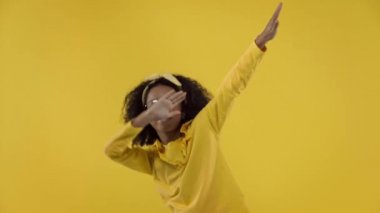 Sarı renkte dans eden mutlu Afrikalı Amerikalı çocuk.