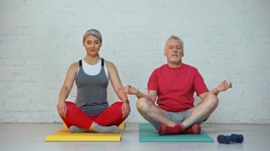 Son sınıf ve ırklar arası çiftler spor paspasları üzerinde meditasyon yapıyorlar. 