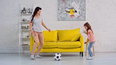 Anne ve kızı oturma odasında futbol oynuyorlar. 