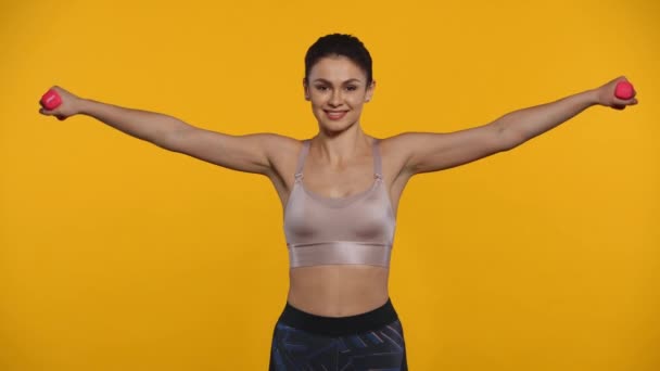 Gülümseyen Sporcu Kadın Sarı Renkli Dambıllarla Egzersiz Yapıyor — Stok video
