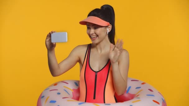 笑着穿泳衣的女孩在用黄色隔离的智能手机上进行视频通话 — 图库视频影像