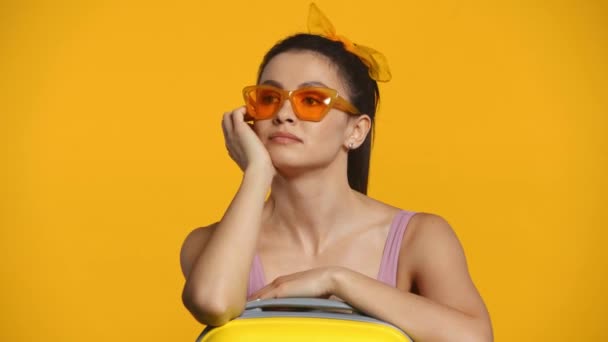 Mujer Pensativa Gafas Sol Cerca Maleta Aislada Amarillo — Vídeo de stock
