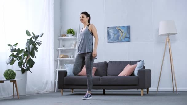 Aantrekkelijke Sportvrouw Stretching Benen Thuis — Stockvideo