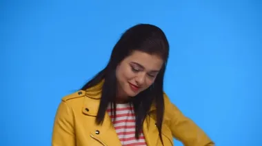 Sarı ceketli çekici bir kız. Mavi renkli kameraya gülümsüyor.