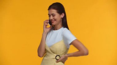 Sarıda izole edilmiş akıllı telefondan konuşan gülümseyen kız.