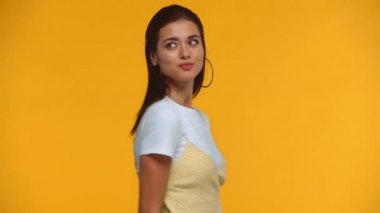 Gülümseyen kız sarıya izole edilmiş kameraya başparmağını gösteriyor.