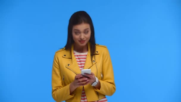 Chica Sonriente Con Teléfono Inteligente Agitando Mano Cámara Aislada Azul — Vídeo de stock