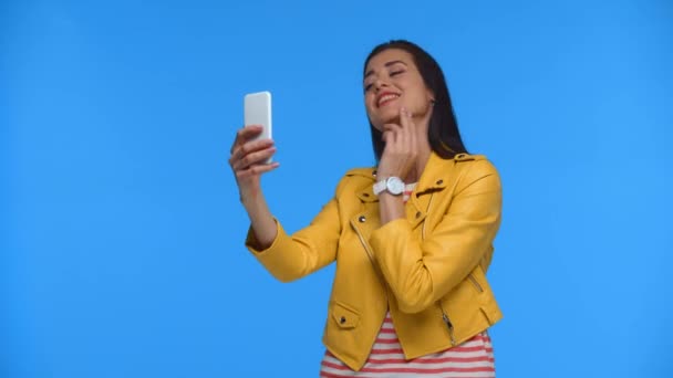 Glimlachend Meisje Geel Jasje Selfie Met Smartphone Geïsoleerd Blauw — Stockvideo