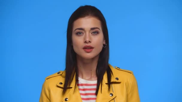 穿着黄色夹克的迷人女孩在蓝色上表现出沉默的迹象 — 图库视频影像