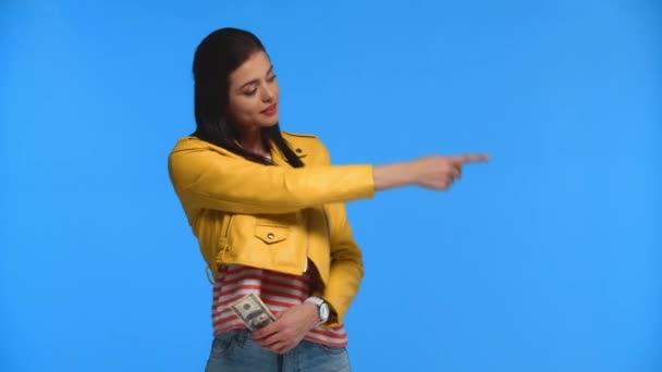 Sorrindo Menina Apontando Com Dedo Segurando Dinheiro Isolado Azul — Vídeo de Stock