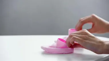 Masanın yanında pembe bebek paçası tutan kadın görüntüsü. 