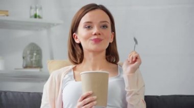 Kanepede dondurma yiyen gülümseyen kadın. 