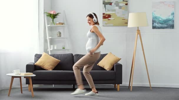 Šťastná Těhotná Žena Sluchátkách Tančí Chytrým Telefonem Doma — Stock video