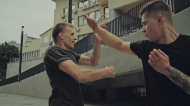 Saldırgan adamlar bina yakınında sokakta kavga ediyorlar. 