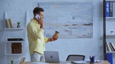 Mutlu iş adamı akıllı telefondan konuşuyor ve kahve içiyor. 