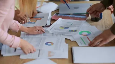 Çalışma masasındaki grafikler ve grafiklerin yakınındaki iş insanlarının kırpılmış görüntüsü 