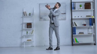 Takım elbiseli sakallı işadamı havaya para atıyor. 