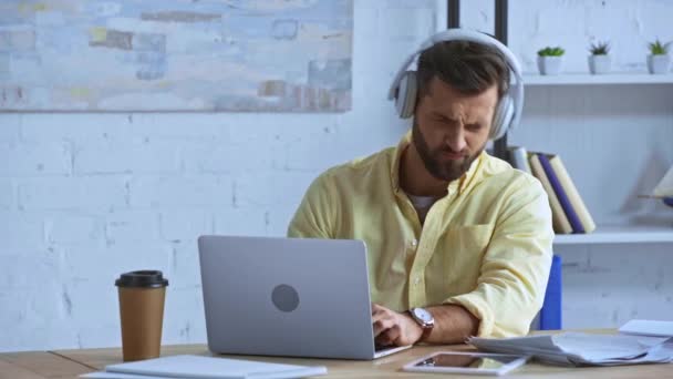 Skäggig Man Lyssnar Musik Hörlurar Nära Bärbar Dator Kontoret — Stockvideo