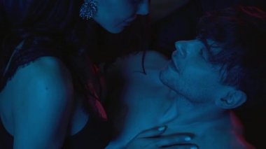 Kanepede kaslı bir adama dokunan seksi bir kadın manzarası.