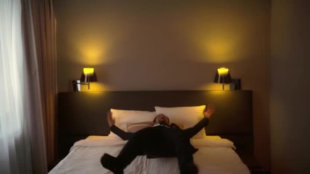 穿着西装的快乐商人在旅馆里跳上了床 — 图库视频影像