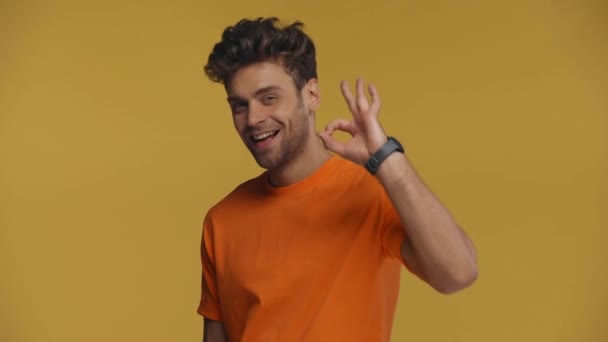 Usmívající Muž Ukazuje Pořádku Gesto Kameru Izolované Žluté — Stock video