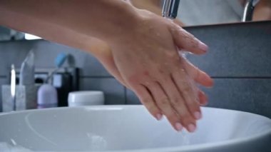 Banyoda ellerini yıkayan genç bir kadın manzarası.