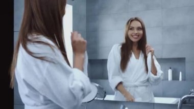 Banyoda aynanın önünde dans eden ve öpüşen çekici genç bir kadın.