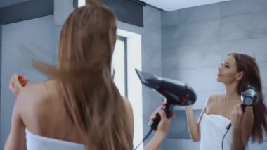 Banyoda saçlarını kurutan banyo havlusuyla güzel genç bir kadın.