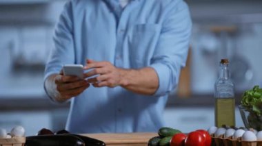 Kesilmiş insan görüntüsü akıllı telefonla taze malzemelerin fotoğrafını çekiyor.