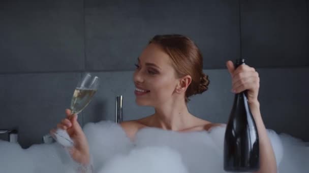 シャンパンと泡風呂でお祝いする魅力的な若い女性 — ストック動画