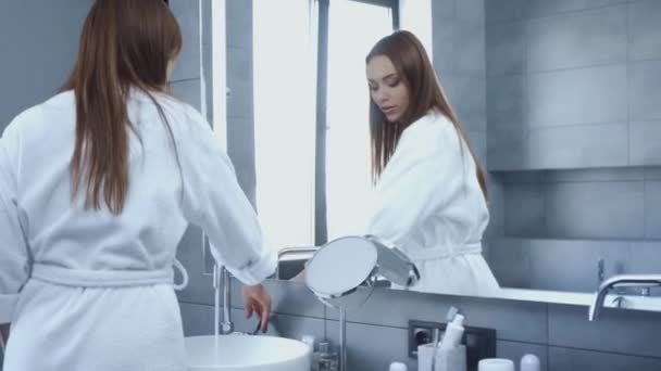 年轻美丽的女人在浴室里一边洗手一边看着镜子 — 图库视频影像