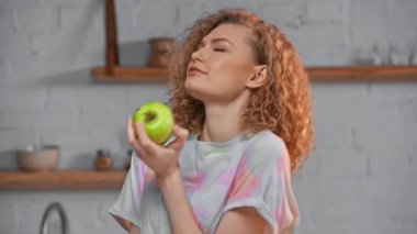 Mutfakta yeşil elma tutan gülümseyen kız. 