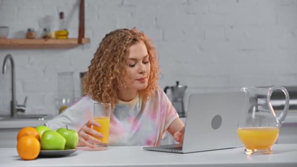 Lachende Vrouw Die Laptop Gebruikt Sinaasappelsap Drinkt Keuken — Stockvideo