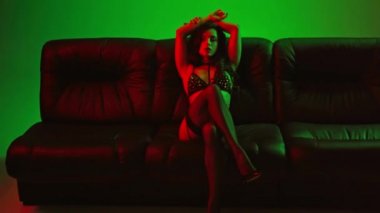 Yeşile oturmuş iç çamaşırlı seksi bir kadın. 