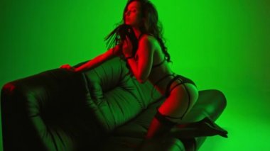 Yeşil kamçılı, iç çamaşırlı seksi bir kadın.