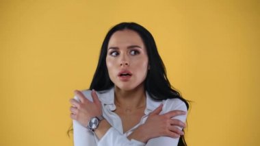 Güzel, korkmuş ve şok olmuş iş kadını sarıya izole edilmiş kameraya bakıyor.