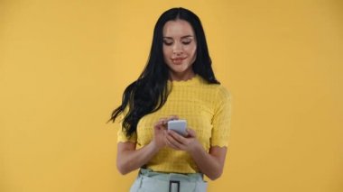Akıllı telefonlu heyecanlı kız sarı kameraya evet işareti yapıyor.
