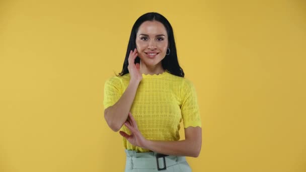 Attraente Ragazza Toccando Capelli Sorridendo Alla Fotocamera Isolata Sul Giallo — Video Stock