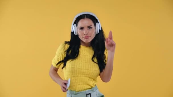 スマートフォンを持っているヘッドフォンで女性と黄色に隔離されたダンス — ストック動画