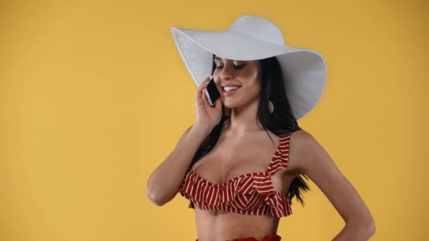 Chica Feliz Sombrero Sol Hablando Teléfono Inteligente Aislado Amarillo — Vídeo de stock