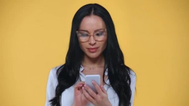 İş kadını sarıda izole edilmiş akıllı telefonla konuşurken hoparlör kullanıyor.