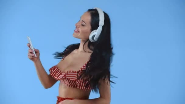 Menina Sorridente Fones Ouvido Segurando Smartphone Dançando Isolado Azul — Vídeo de Stock