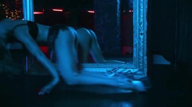 Striptiz kulübünde aynanın yanında dans eden baştan çıkarıcı striptizci. 
