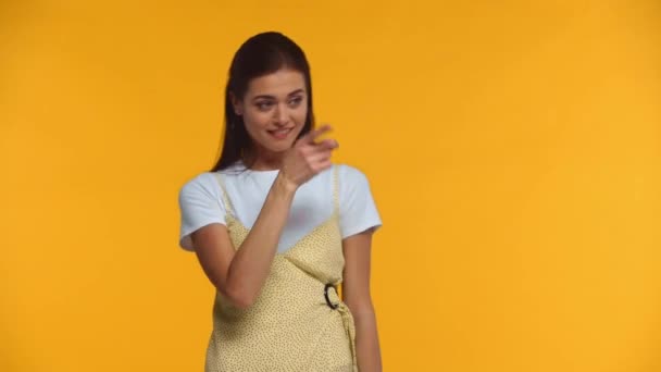 Веселая Девушка Машет Руками Смотрит Камеру Изолированную Желтый — стоковое видео
