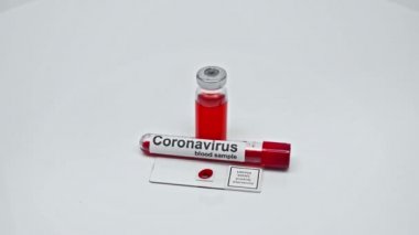 Test tüpünde koronavirüs kanı örneği ve aşı yakınında laboratuvar camı.