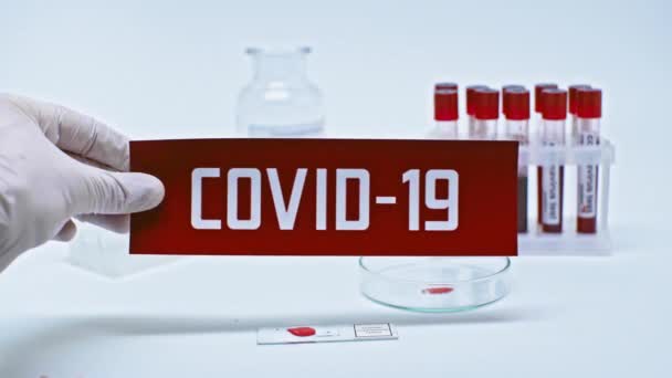研究室でCovid 19カードを持っている科学者のクロップドビュー — ストック動画
