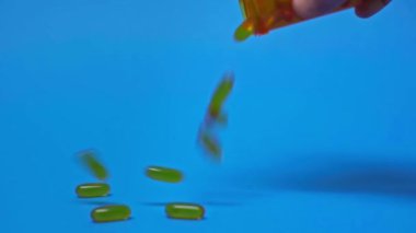Mavi arka planda kavanozdan düşen hapların yavaş hareketi